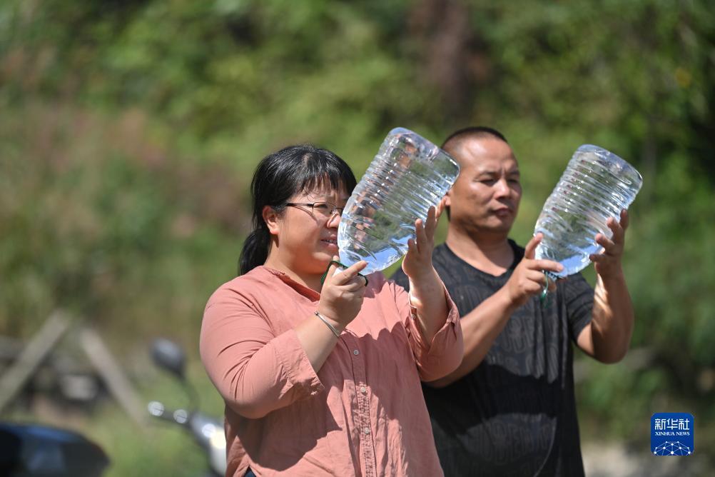 楊寧（左）在查看村民剛剛采集的水樣，為山泉水引水工程做準(zhǔn)備（10月8日攝）。新華社記者 黃孝邦 攝